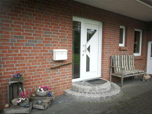 a brick house with a white door and a chair at FeWo Grüne Wiese 