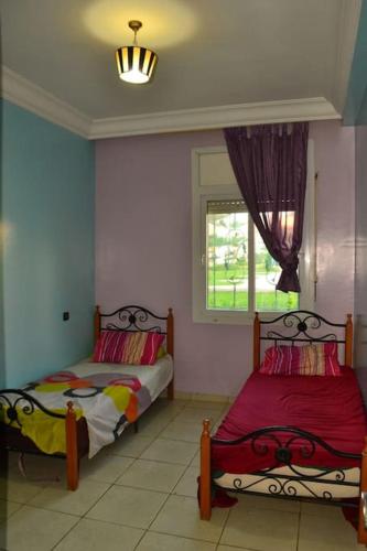 een slaapkamer met 2 bedden en een raam bij Luxury flat in Mohamadia. in Mohammedia