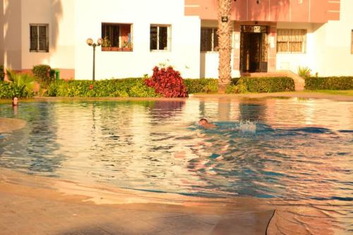 een man zwemmend in een zwembad in een gebouw bij Luxury flat in Mohamadia. in Mohammedia
