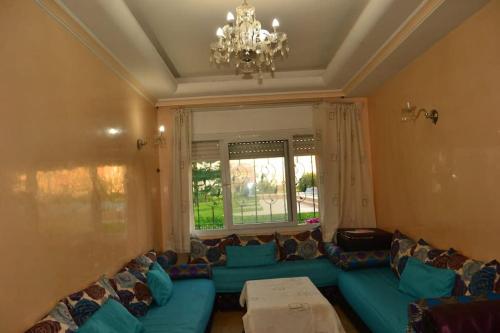 a living room with a blue couch and a chandelier at Luxury flat in Mohamadia. in Mohammedia