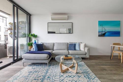 ein Wohnzimmer mit einem Sofa und einem Tisch in der Unterkunft Beautiful 2BR APT with Balcony Pool and Gym in Melbourne
