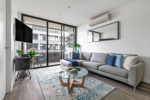 ein Wohnzimmer mit einem Sofa und einem Tisch in der Unterkunft Beautiful 2BR APT with Balcony Pool and Gym in Melbourne