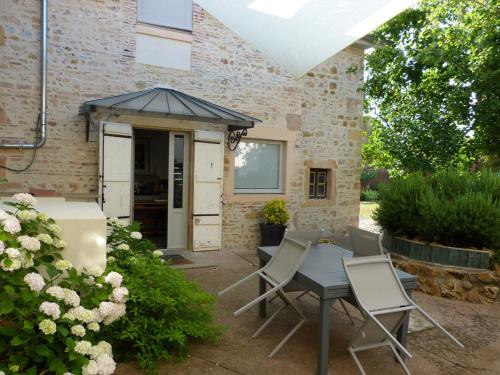 eine Terrasse mit einem Tisch und Stühlen vor einem Gebäude in der Unterkunft Chambres d'hôtes Les Pergolas in Marcigny