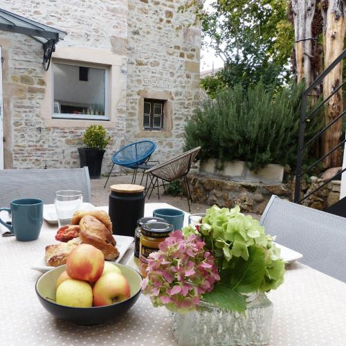 una mesa con un bol de frutas y flores en ella en Chambres d'hôtes Les Pergolas, en Marcigny