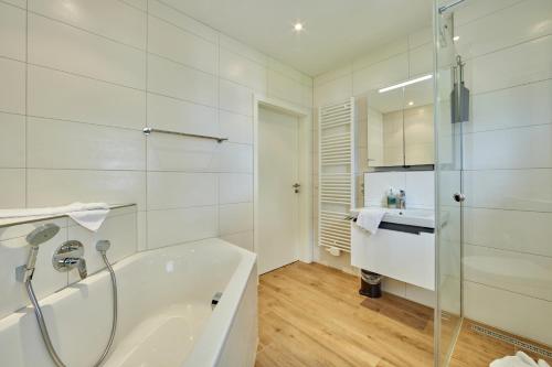 a white bathroom with a tub and a sink at BergIdylle 2 in Garmisch-Partenkirchen