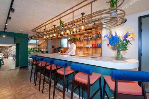 a man standing behind a bar with blue stools at Hotel Nicolaas Witsen in Amsterdam