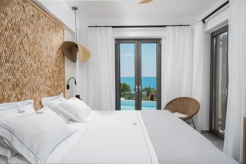 a bedroom with a bed and a view of the ocean at Mnḗmē Suites & Villas in Kastrí