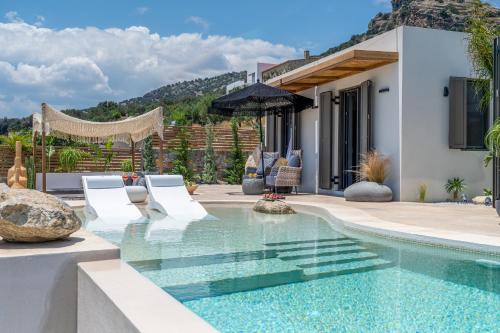 a pool with chairs and an umbrella in a house at Mnḗmē Suites & Villas in Kastrí