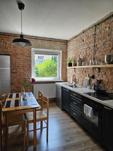 eine Küche mit einem Tisch und einer Ziegelwand in der Unterkunft Apartament Stanowisko in Gliwice