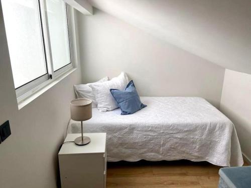 a white bedroom with a bed with blue pillows at Flat moderno e central em Braga in Braga