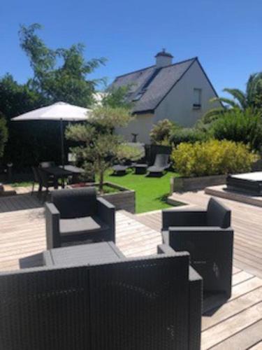 un patio avec des chaises, une table et un parasol dans l'établissement Gîte de charme le Ty zen Breizh ( 4/6 pers ), à Auray
