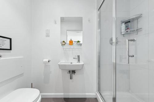 een witte badkamer met een wastafel en een douche bij Sleep6 In Leicester Square, Soho VR7 in Londen