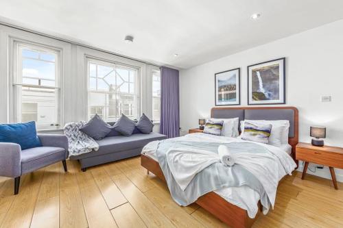 een slaapkamer met een bed en een bank bij Sleep6 In Leicester Square, Soho VR7 in Londen