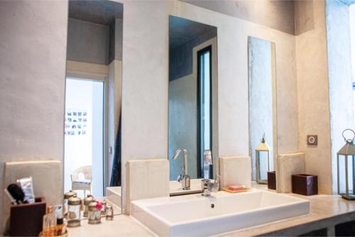 La salle de bains est pourvue d'un grand lavabo blanc et d'un miroir. dans l'établissement La Nomade - Maison contemporaine avec piscine - Toulouse, à Toulouse