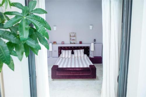 - une chambre avec un lit et une grande plante dans l'établissement La Nomade - Maison contemporaine avec piscine - Toulouse, à Toulouse