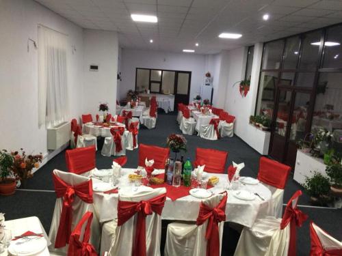 une salle de banquet avec des tables blanches et des chaises rouges dans l'établissement Pensiunea Rebeca, à Bughea de Sus