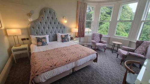 a bedroom with a large bed with a large headboard at Makeney Hall Hotel in Derby