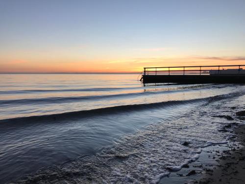 a beach with a pier and the ocean at sunset at Sundsgården hotell & konferens in Helsingborg