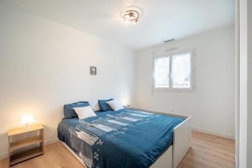 1 dormitorio con cama con sábanas azules y ventana en Entre lacs & Océan - Maison climatisée avec jardin, en Vielle-Saint-Girons
