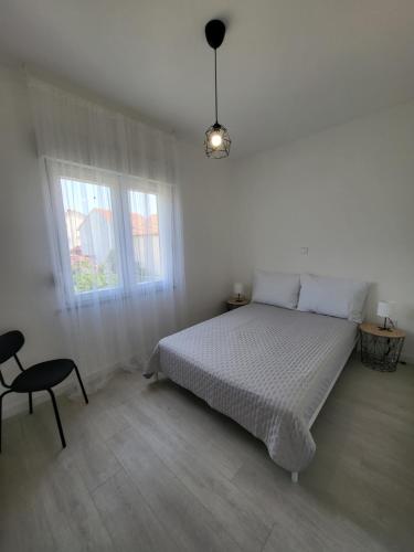 a white bedroom with a bed and a chair at Red Hill apartment in Zaboric