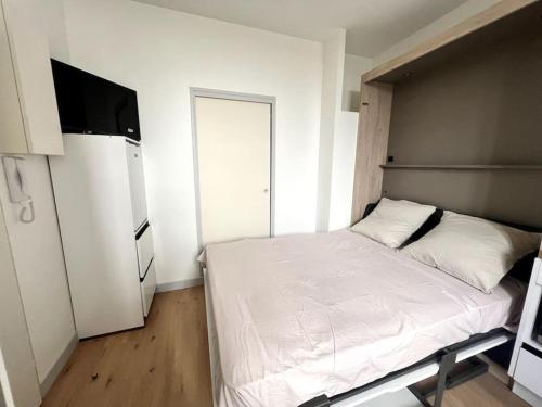 ein kleines Schlafzimmer mit einem weißen Bett und einem Kühlschrank in der Unterkunft Le Petit Albert - Coeur de ville in La Rochelle