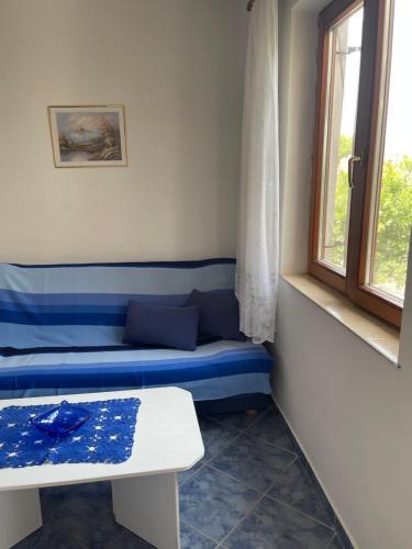 um quarto com um banco azul e uma janela em Apartmani Ksenija em Murter