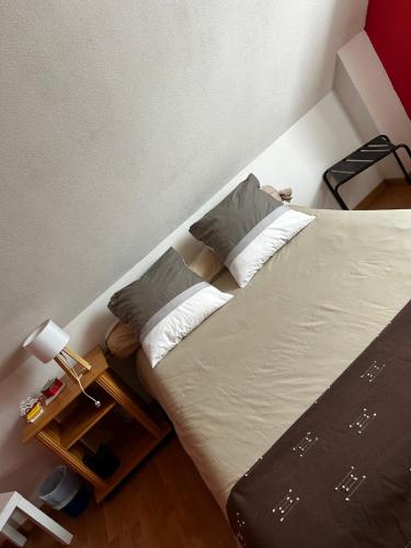 ein großes Bett mit zwei Kissen und einem Nachttisch in der Unterkunft Maison privée in Kingersheim