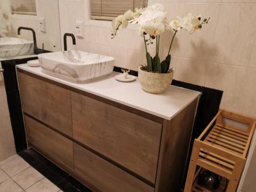 a bathroom with a sink and a vase of flowers on a counter at Pukaki Holiday Apartments in Rotorua