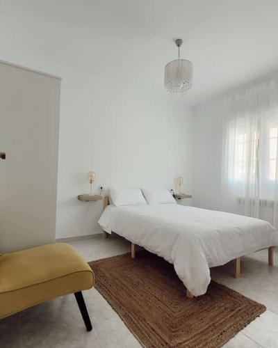 une chambre blanche avec un grand lit et une chaise dans l'établissement Casa Tonino: Encantadora casa junto al Río Duero, à Zamora