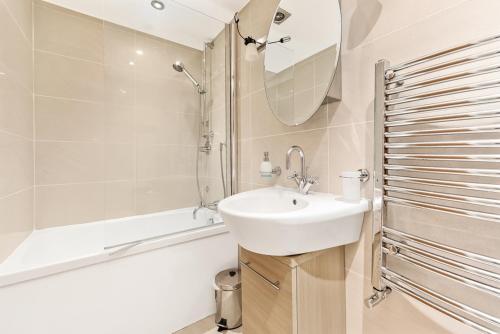 a white bathroom with a sink and a bath tub at LONDON ONE BED ANNEX in London