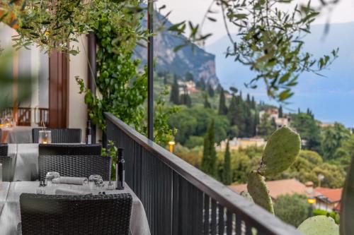 a balcony with tables and chairs and a view of the mountains at Hotel Meandro - Lake View in Gargnano