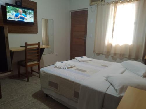 Hotel Venice Ubatuba في أوباتوبا: غرفة نوم بسرير ومكتب وتلفزيون
