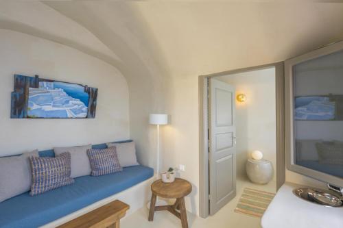 Oia Waves by SV في أويا: غرفة معيشة مع أريكة زرقاء وتلفزيون