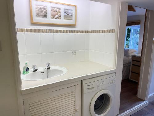 a bathroom with a sink and a washing machine at 10 The Warren, amazing seaviews from every floor! in St Ives