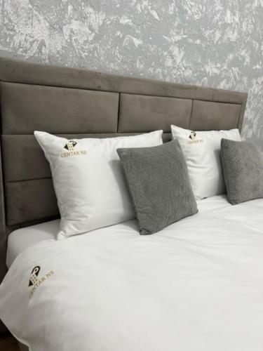 a bed with white sheets and pillows in a room at Centar NS 5 in Novi Sad