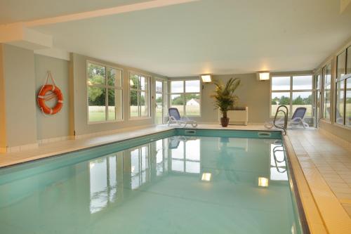 een zwembad in een huis met ramen bij Résidence VTF Les Allées du Green in Levernois