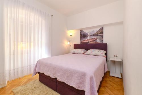 um quarto com uma cama grande e um cobertor rosa em SNJEŽANA em Mali Lošinj