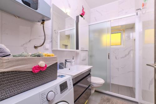 uma casa de banho branca com um lavatório e um WC em SNJEŽANA em Mali Lošinj