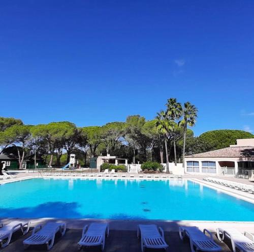 uma grande piscina com cadeiras azuis e árvores em Studio climatisé avec piscine em Saint-Raphaël