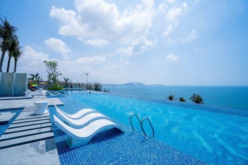uma piscina com duas cadeiras e o oceano em S1823 Apec Mandala Cham Bay em Ấp Thiẹn Ái