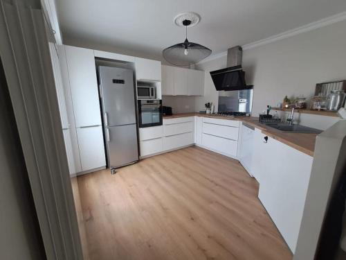 a kitchen with white cabinets and a wooden floor at Maison paisible et ensoleillée in Avignon