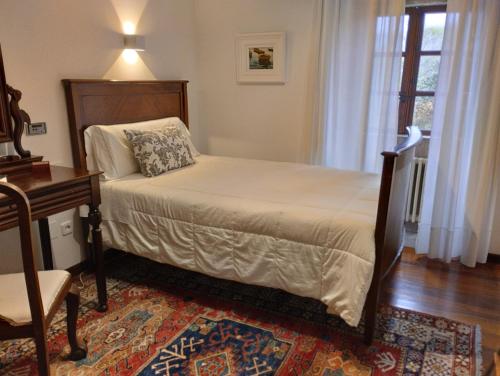 a bedroom with a bed and a desk and a window at Casa Pontevella in Amés