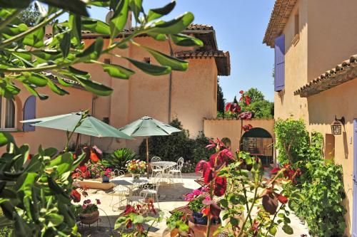 patio ze stołami, parasolami i kwiatami w obiekcie Le Mazet des Mûres w mieście Grimaud