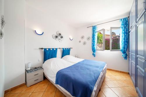 1 dormitorio con 1 cama con cortinas azules y ventana en Villa La Cigalette Gaiasvillas, en Théoule-sur-Mer