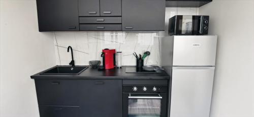 een keuken met een zwart aanrecht en een koelkast bij Golden - Éden - superbe 2 pièces de standing en hypercentre in Vichy