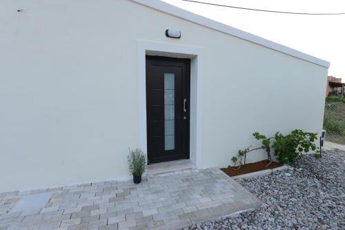 a black door on the side of a white house at Stablus house in Alykes Potamou