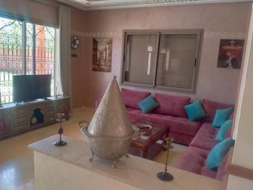 een woonkamer met een rode bank en een tv bij Villa khaddouj Marrakech in Marrakesh