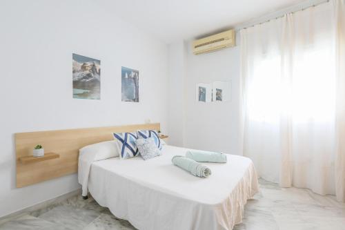 a white bedroom with a bed with pillows on it at Azahar Fibes in Seville