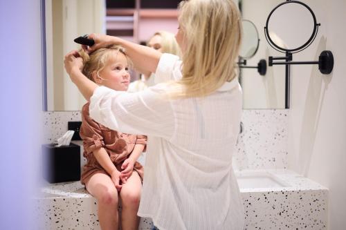 a woman brushing a little girls hair in a bathroom at The CORNR Hotel in Nieuwpoort