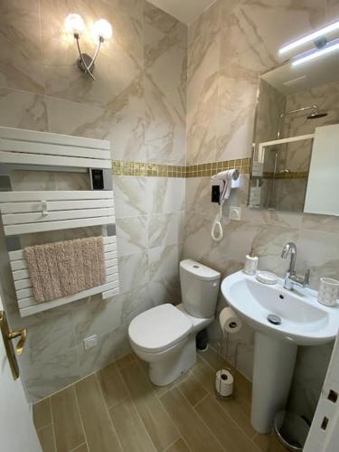 La salle de bains est pourvue de toilettes blanches et d'un lavabo. dans l'établissement Au coeur de Brantôme : superbe appartement, à Brantôme